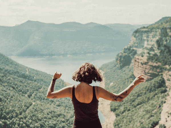 sense of self - confidence - a woman standing on a cliff overlooking a valley
