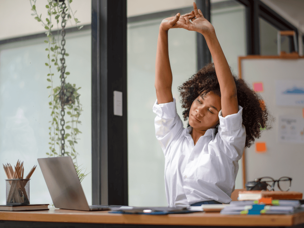 quick self care ideas - a woman stretching her arms at work