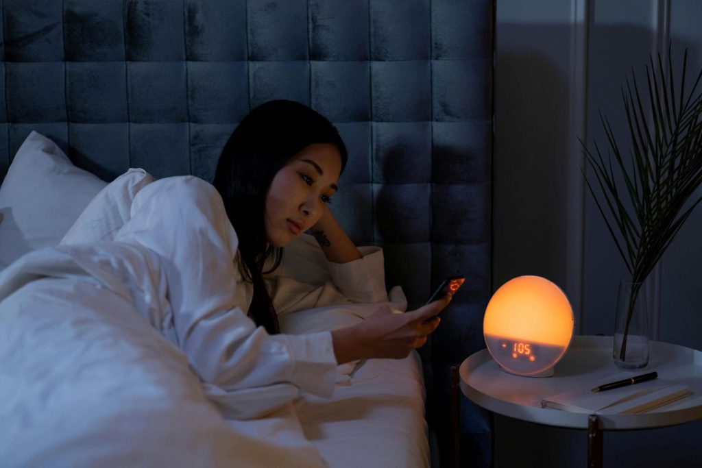 digital detox - a woman lying in bed looking at a phone