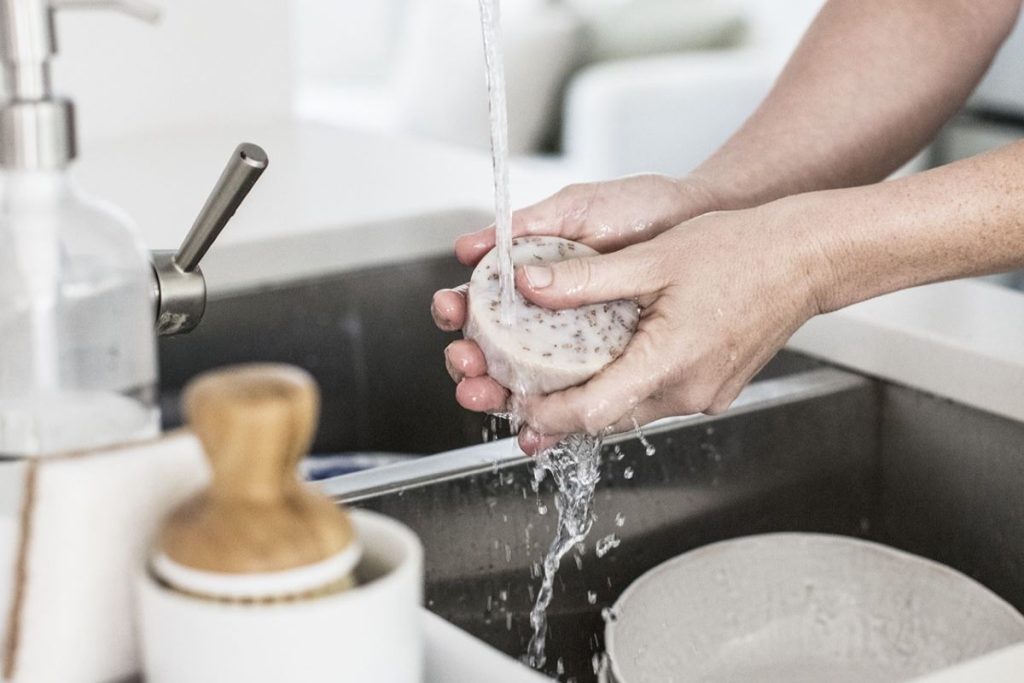a woman washing her hands in the kitchen sink full of dishes - feeling unproductive