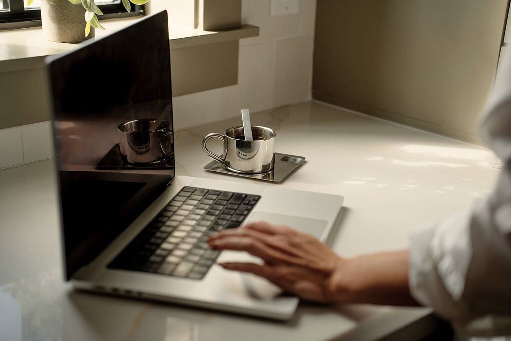 a person typing on a laptop on a clear counter top - minimalist productivity